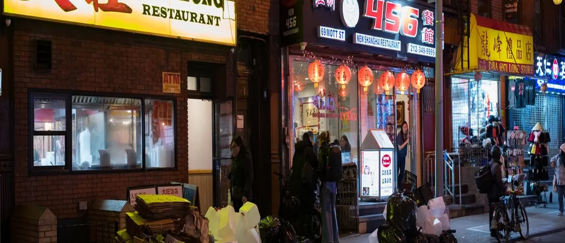 Bustling street scene on Mott Street in Chinatown Manhattan with vibrant shop signs and fresh food counters